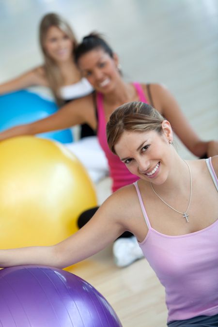 Group of women at the gym smiling with a pilates ball