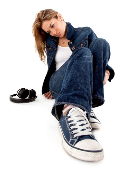 Woman sitting on the floor next to headphones - isolated over a whie background