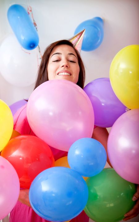 Beautiful girl smiling and covered with balloons in a birthday party