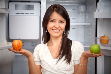 Beautiful woman taking fruits from the fridge and smiling