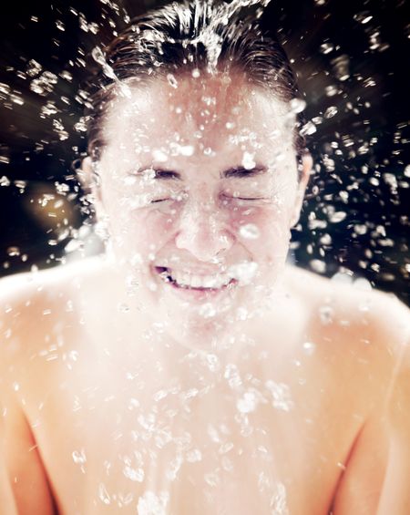 Beautiful woman refreshing her face with a water splash