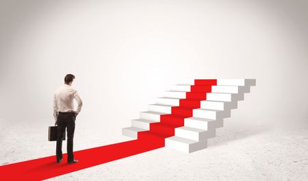 A successful businessman with briefcase standing on red carpet in front of steps in white space concept