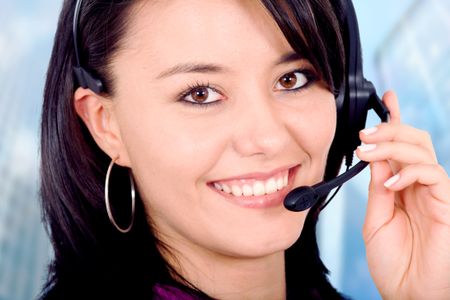 customer service girl smiling with hand on headset - in an office environment