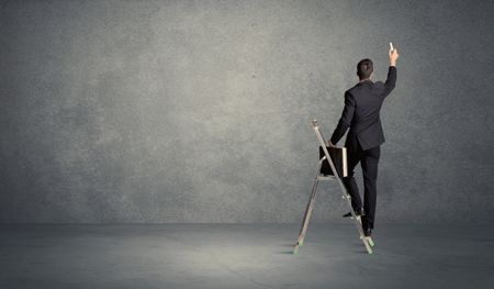 A man standing on ladder drawing with chalk in his hand on clear wall pattern background