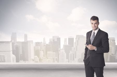 A young adult businessman standing in front of city landscape with skyscraper buildings and clouds concept