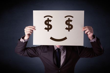 Young casual businessman hiding behind a greedy face drawing on cardboard