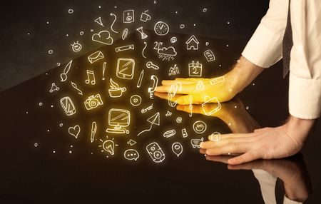 Male hands touching interactive table with yellow mixed media icons on it