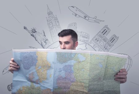 Handsome young man holding a map with famous sightseeing destinations above his head