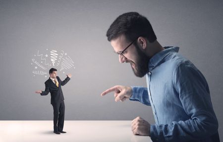 Young professional businessman being angry with an other miniature businessman who has scribbles above his head