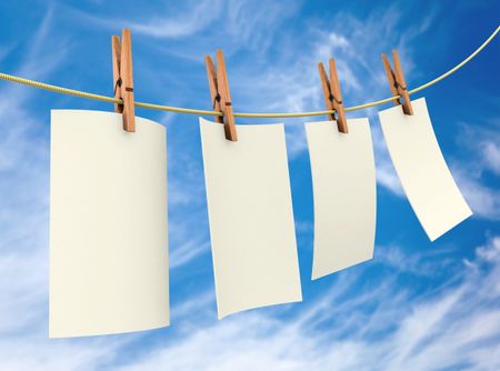 Clothes pin holding white sheets of paper outdoors