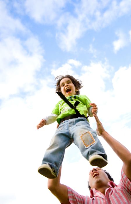father and son having fun together outdoors in front of a blue sky