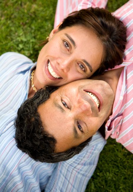 couple portrait on the floor outdoors where both are smiling and looking happy