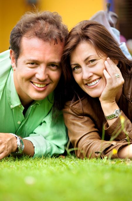 couple portrait on the floor outdoors where both are smiling and looking happy