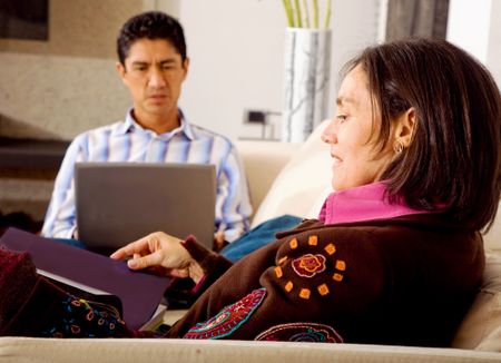 lifestyle couple at home where she is reading while he is on the laptop computer