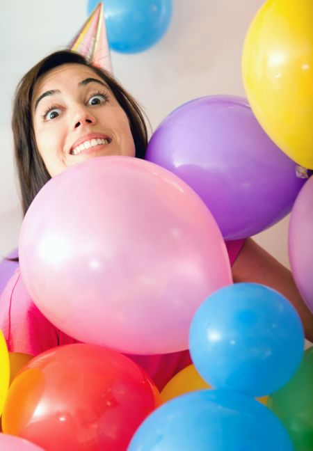 Woman at a birthday party surrounded by colorful balloons