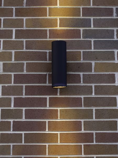 Black cylindrical light fixture on exterior brick wall