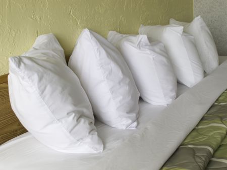 Row of five pillows on hotel bed
