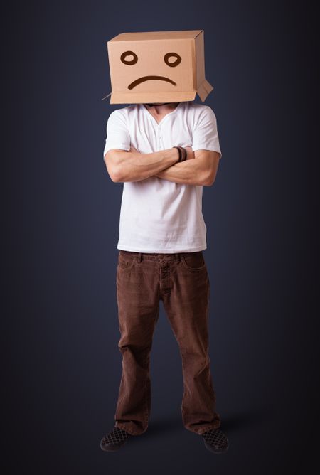 Young man standing with a brown cardboard box on his head with sad face