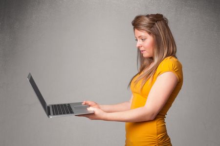 Pretty young woman holding modern laptot