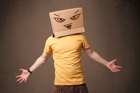 Young man standing and gesturing with a cardboard box on his head with evil face