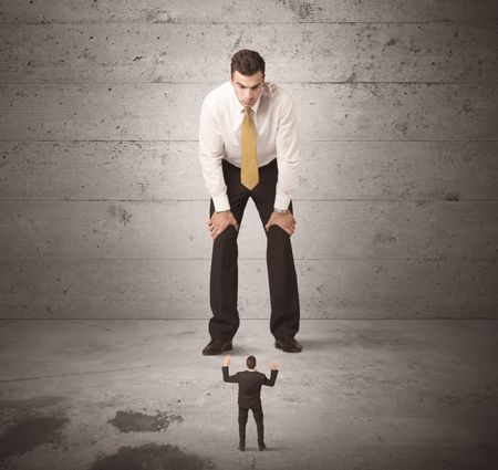 Huge angry business guy looking at small coworker concept on background