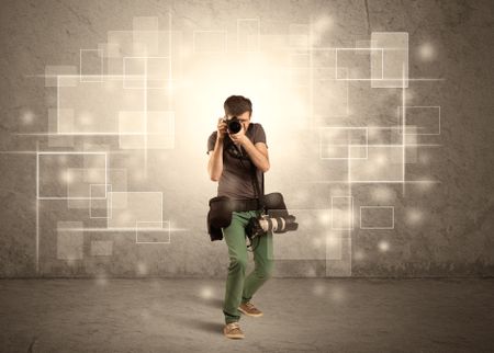 A hobby photographer with professional camera gear and belt shooting in front of brown sepia urban concrete wall full of glowing square illustrations concept