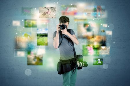 A young amateur photographer with professional camera equipment taking picture in front of blue wall full of faded pictures and glowing lights concept