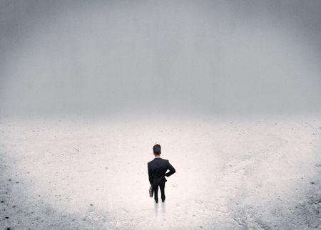 An adult elegant businessman standing in the middle of nowhere in empty grey concrete space background concept