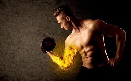 Muscular bodybuilder lifting weight with flaming biceps concept on background