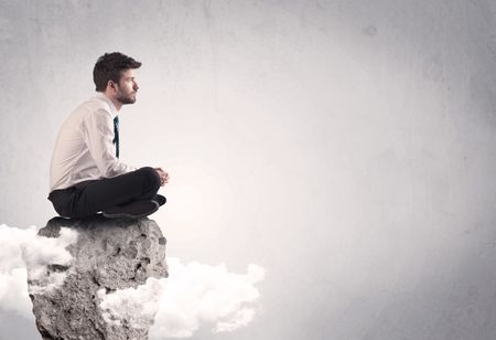 An elegant  smart businessman with laptop sitting in empty grey space on top of a cliff, between clouds concept