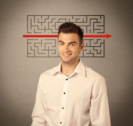 A young handsome business person making facial expression and solving maze with red arrow in front of clear, empty concrete wall background concept