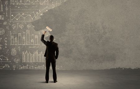 An elegant businessman covering pie charts, statistics, numbers, data, graphs on urban concrete wall with fresh paint using a roller concept