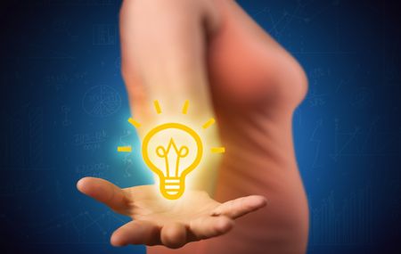 A creative businessman has a great bright idea illustrated by holding a drawn light bulb in the hand concept