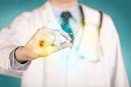 A male doctor in white coat with a stethoscope holding a pill with glowing colorful dots and lines