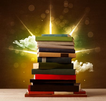 Magical books with ray of lights and colorful clouds on vintage background