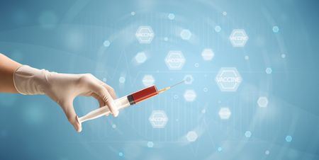 Female doctor hand holding syringe with blue background 