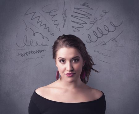 A cute female student making funny face expressions with pressure and problems in her head illustrated by drawn lines, marks and spirals on the urban wall background concept.
