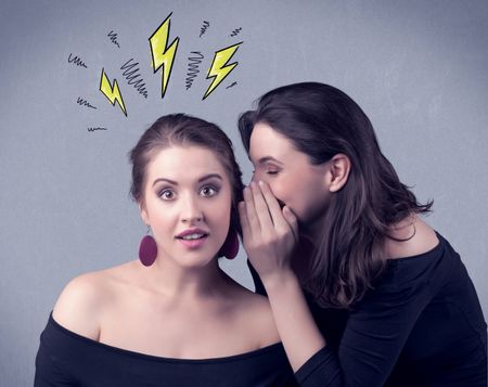 A beautiful girl in black dress sharing secrets to her girlfriend concept with drawn energetic electric yellow signs above her head on the wall background.