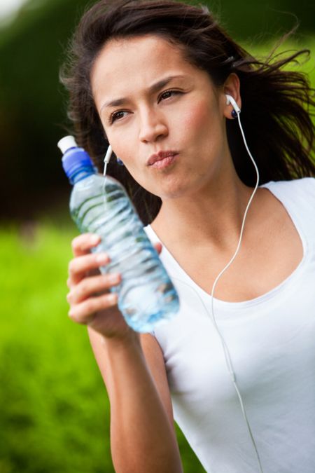 Fit woman drinking water while training outdoors