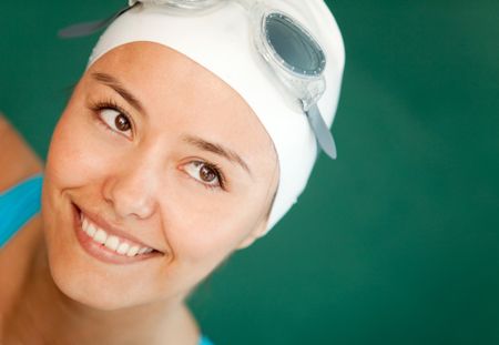 Portrait of a female swimmer wearing hat and goggles and smiling