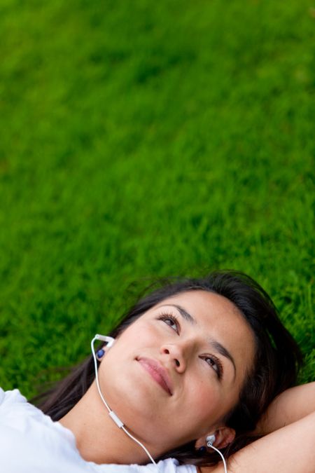 Woman lying on grass listening to music outdoors