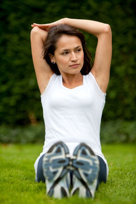 Young woman exercising outdoors stretching one of her arms