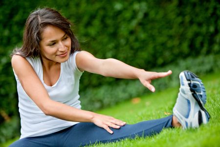 Young woman exercising outdoors stretching one of her legs