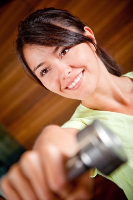 Woman at the gym lifting a free-weight and smiling