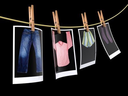 Pin holding photographs of clothes to dry - isolated over a black background