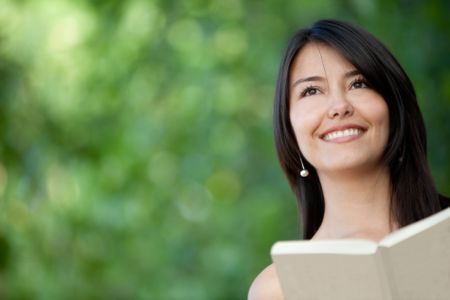 Portrait of a woman reading a book outdoors