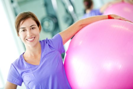 Happy woman at the gym with a pilates ball