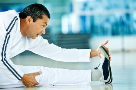 Man doing stretching exercises on the floor at the gym