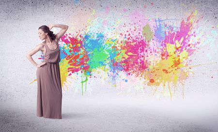 Modern street dancer jumping with colorful paint splashes on back wall concept