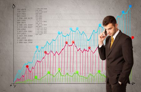 A confident young businessman standing in front of a a chart with graphs and numberswhile talking on the phone concept